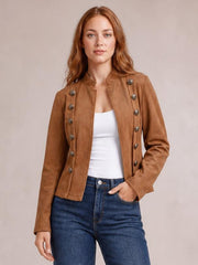 Model wearing a fitted tan open-front jacket with long sleeves, decorative buttons, structured trim, and a cropped silhouette over a white top.