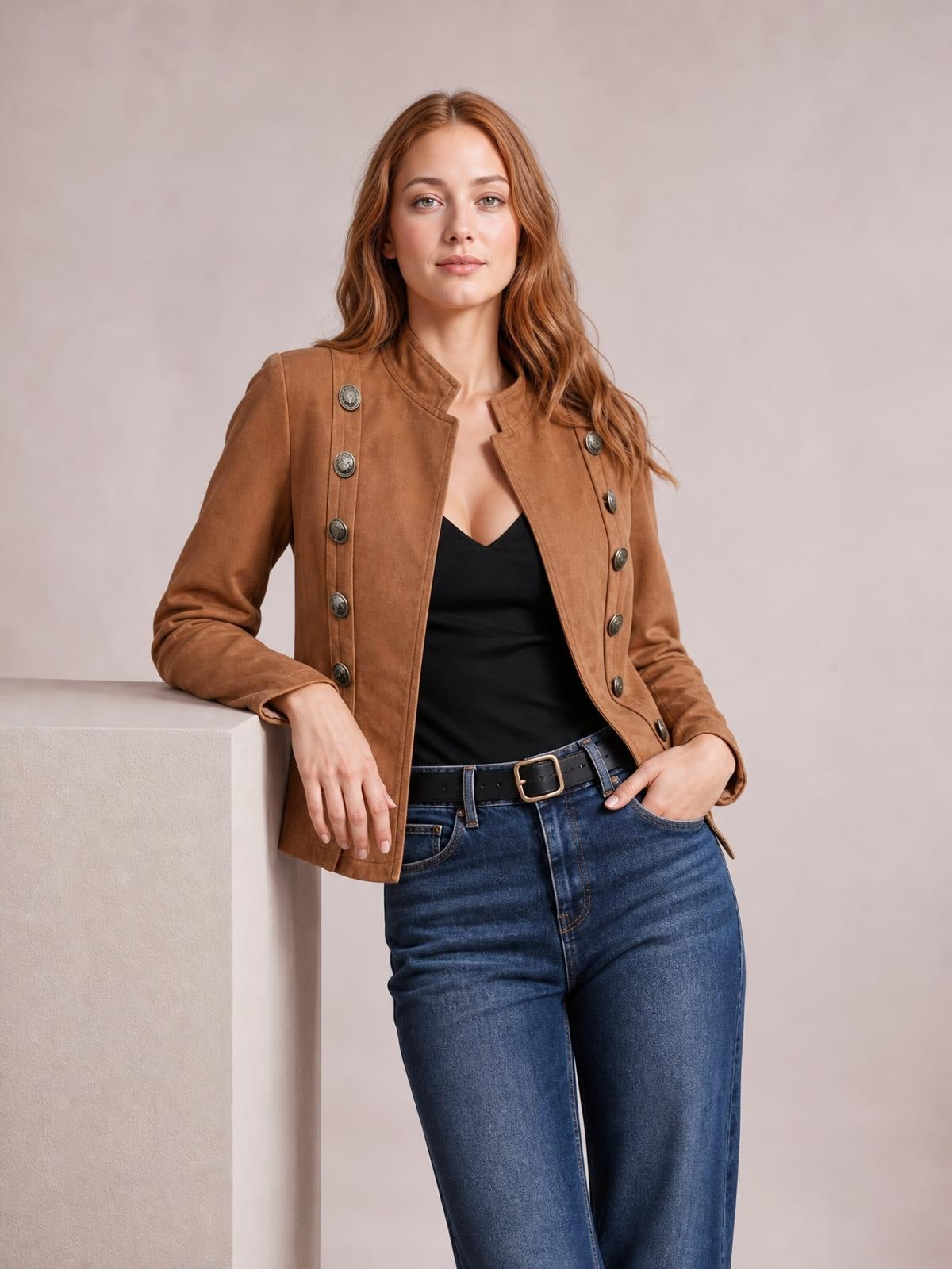 A woman poses in a fitted brown open-front long-sleeve jacket with decorative buttons, structured collarless styling, and a straight silhouette over a black top.