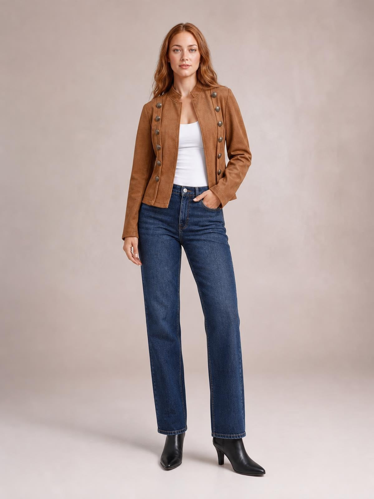 A model wears a brown open-front long sleeve jacket with decorative buttons, a structured waist-length silhouette, and one hand resting in her jeans pocket.