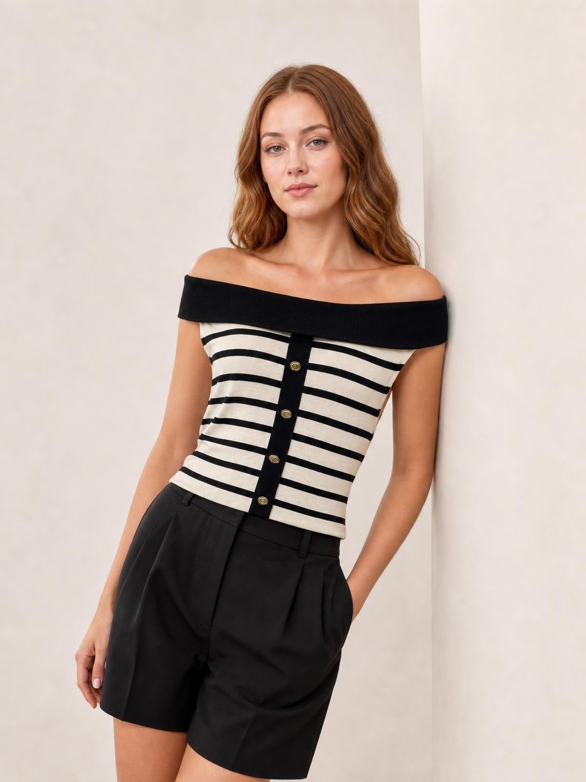 Model wearing a black and cream striped off-shoulder knit top with a fitted silhouette, ribbed neckline, and decorative gold-tone buttons down the front.