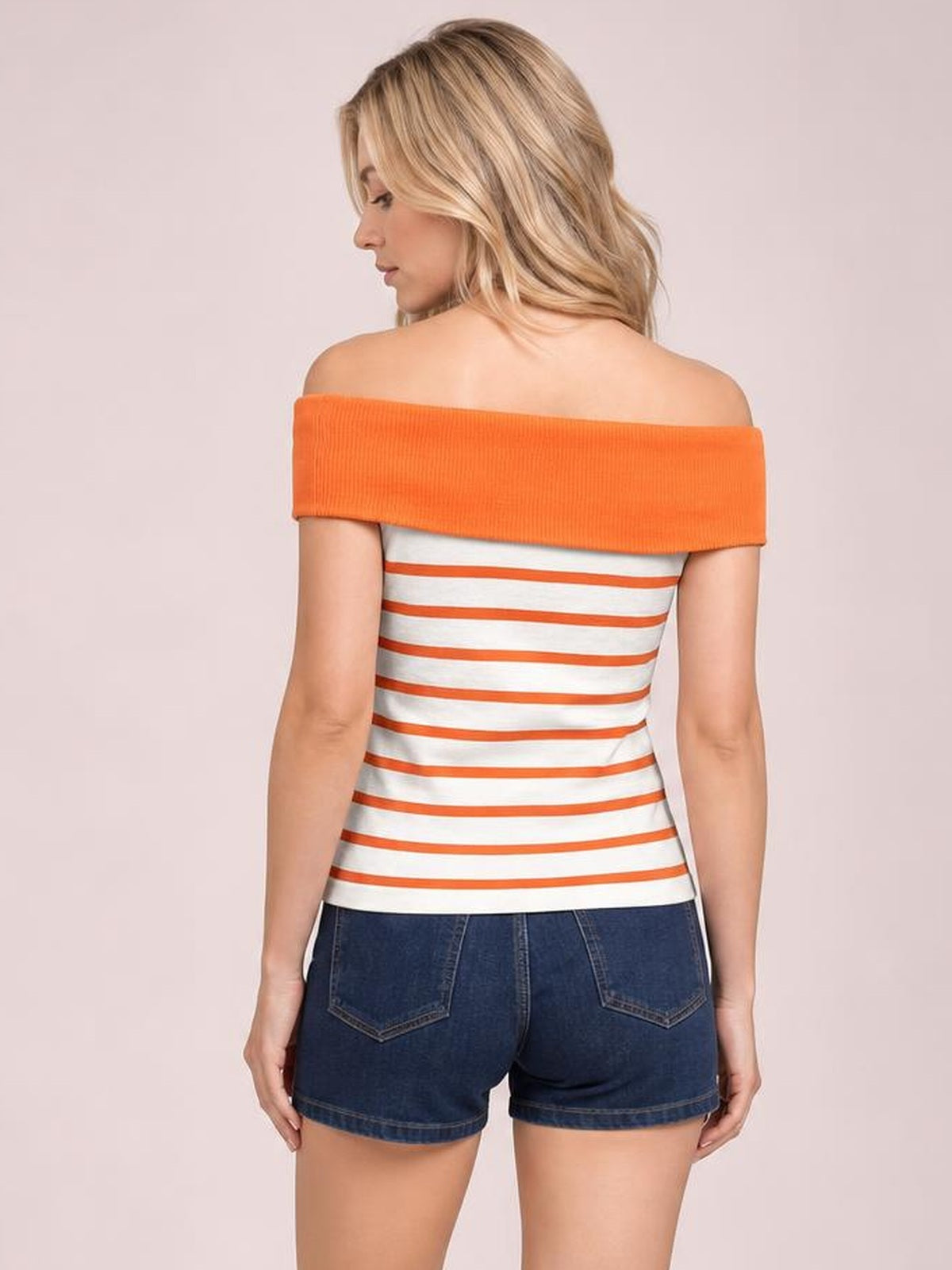 Model seen from the back wearing a fitted white knit top with orange horizontal stripes and a wide off-shoulder orange neckline.