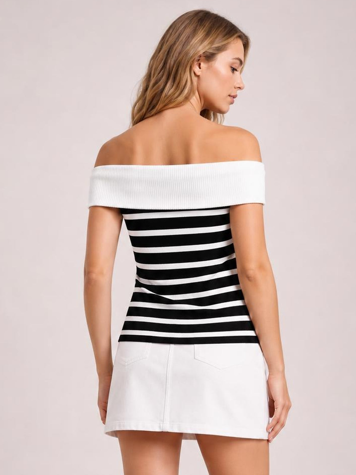 Standing model viewed from the back wearing a black-and-white striped knit top with an off-shoulder neckline, wide ribbed band, and fitted silhouette.