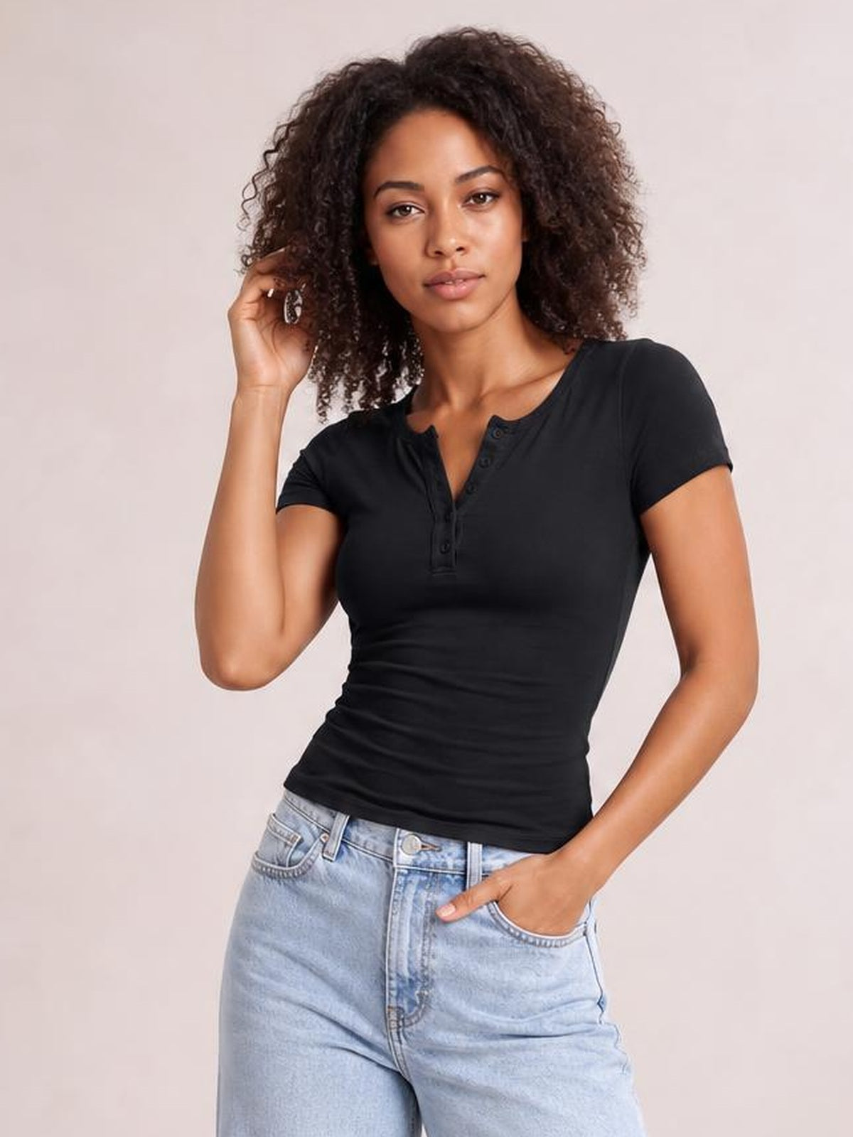 Model poses with one hand in her pocket wearing a fitted black Button Detail Short Sleeve T-Shirt with a notched neckline and button placket.