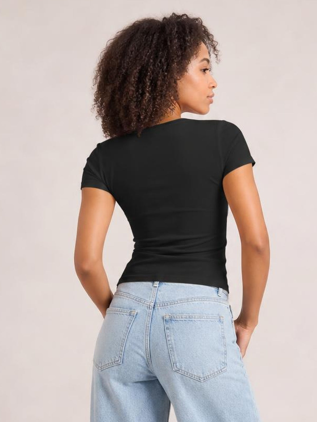 Model shown from behind wearing a black short sleeve T-shirt with a fitted, stretchy silhouette, crew neckline, and smooth opaque construction.