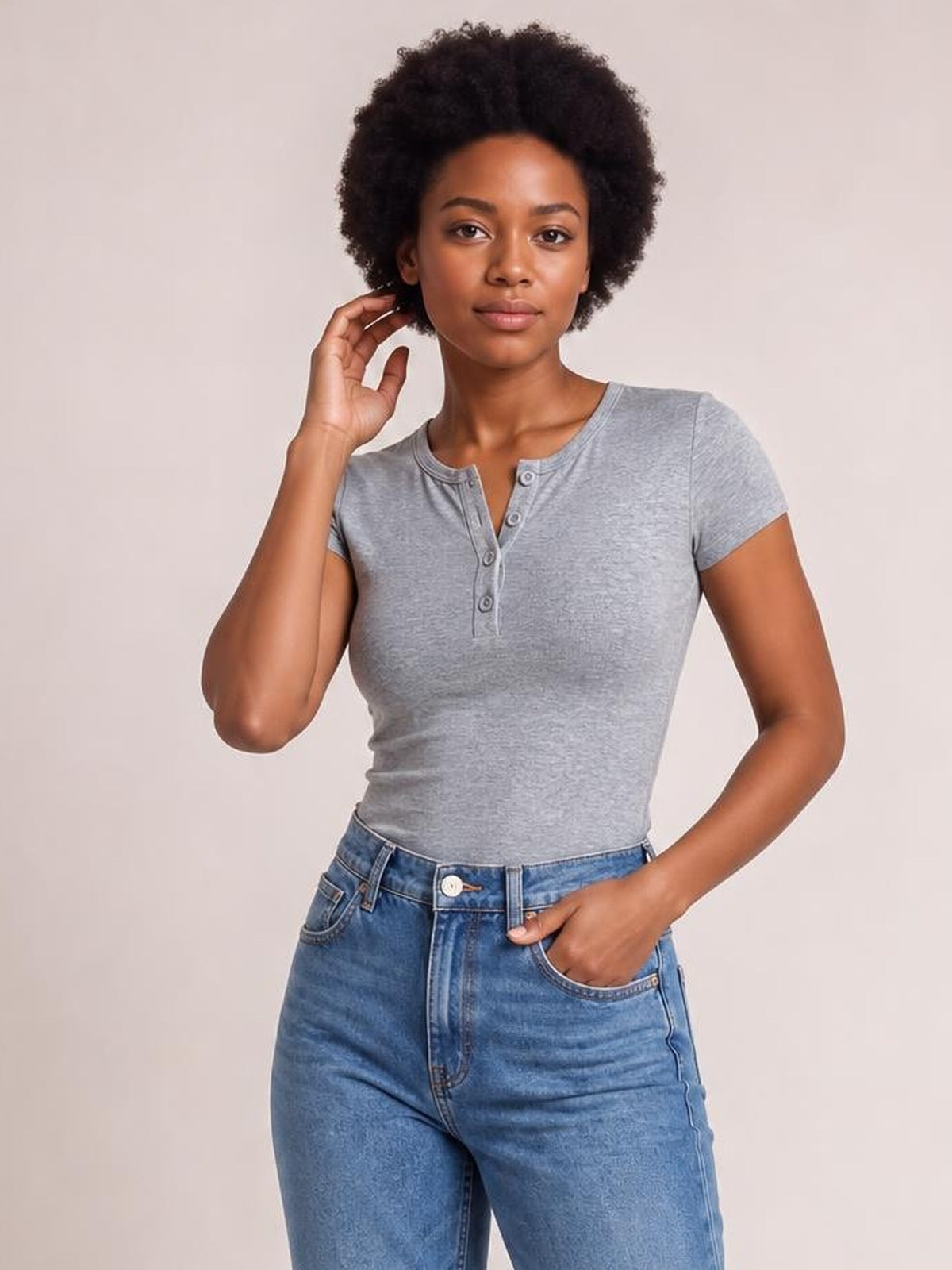 Model wears a gray Button Detail Short Sleeve T-Shirt with a fitted silhouette, round neckline, and button placket, posing with one hand in her jeans pocket.