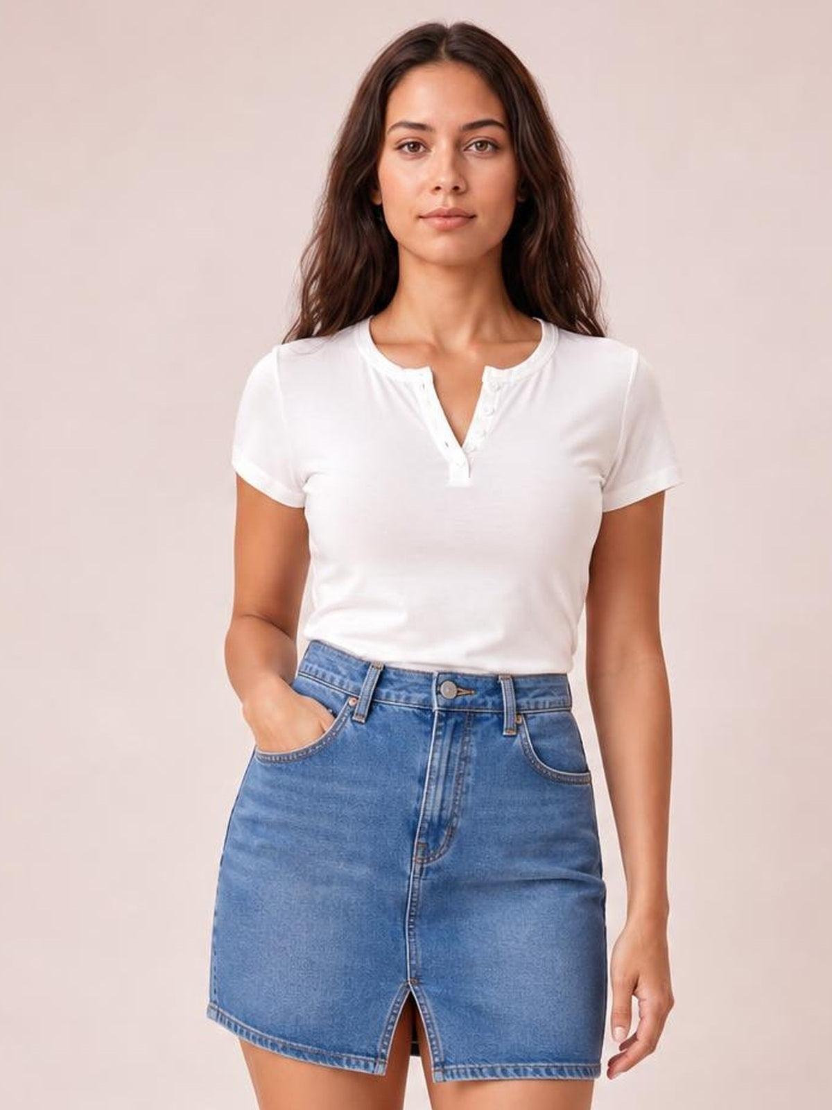 Woman wearing a white button-detail short sleeve T-shirt with a notched neckline and fitted silhouette, posed with one hand in her denim skirt pocket.