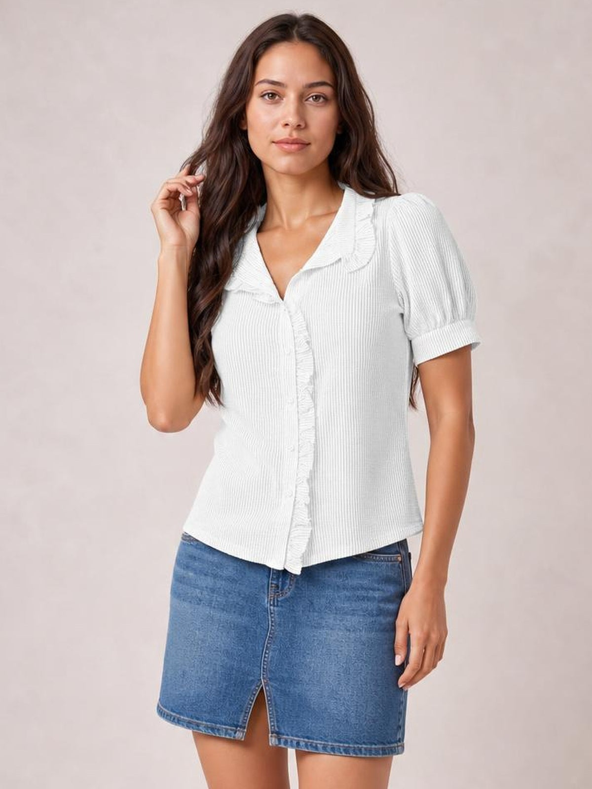 A model poses in a white striped short sleeve button-down shirt with a ruffled placket, collar, gently gathered sleeves, and a fitted silhouette.