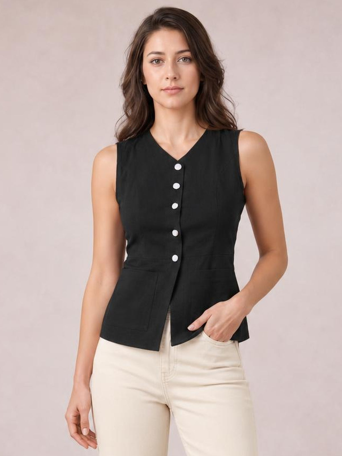 Model wears a black sleeveless button-down top with a V-neck, fitted silhouette, front pockets, and contrasting buttons, posing with one hand in a pocket.