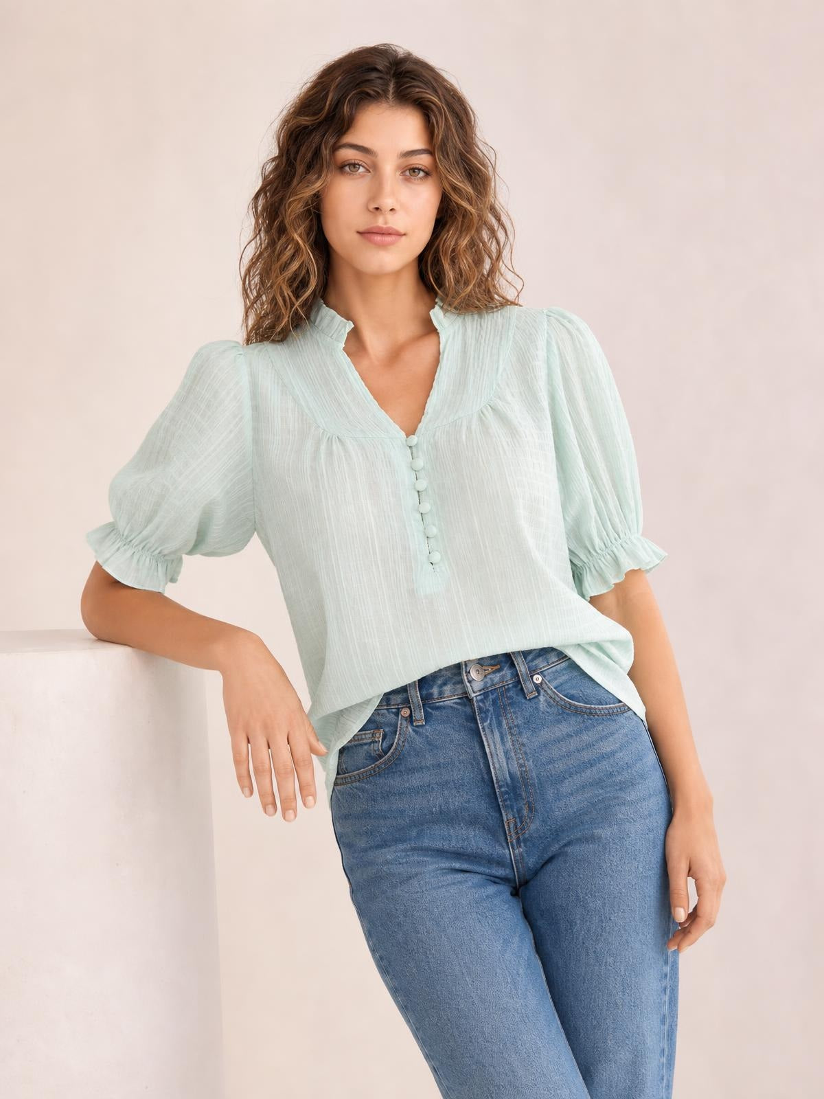 Model wearing a light mint frill notched blouse with ruched texture, button front, and short puff sleeves finished with ruffled cuffs.