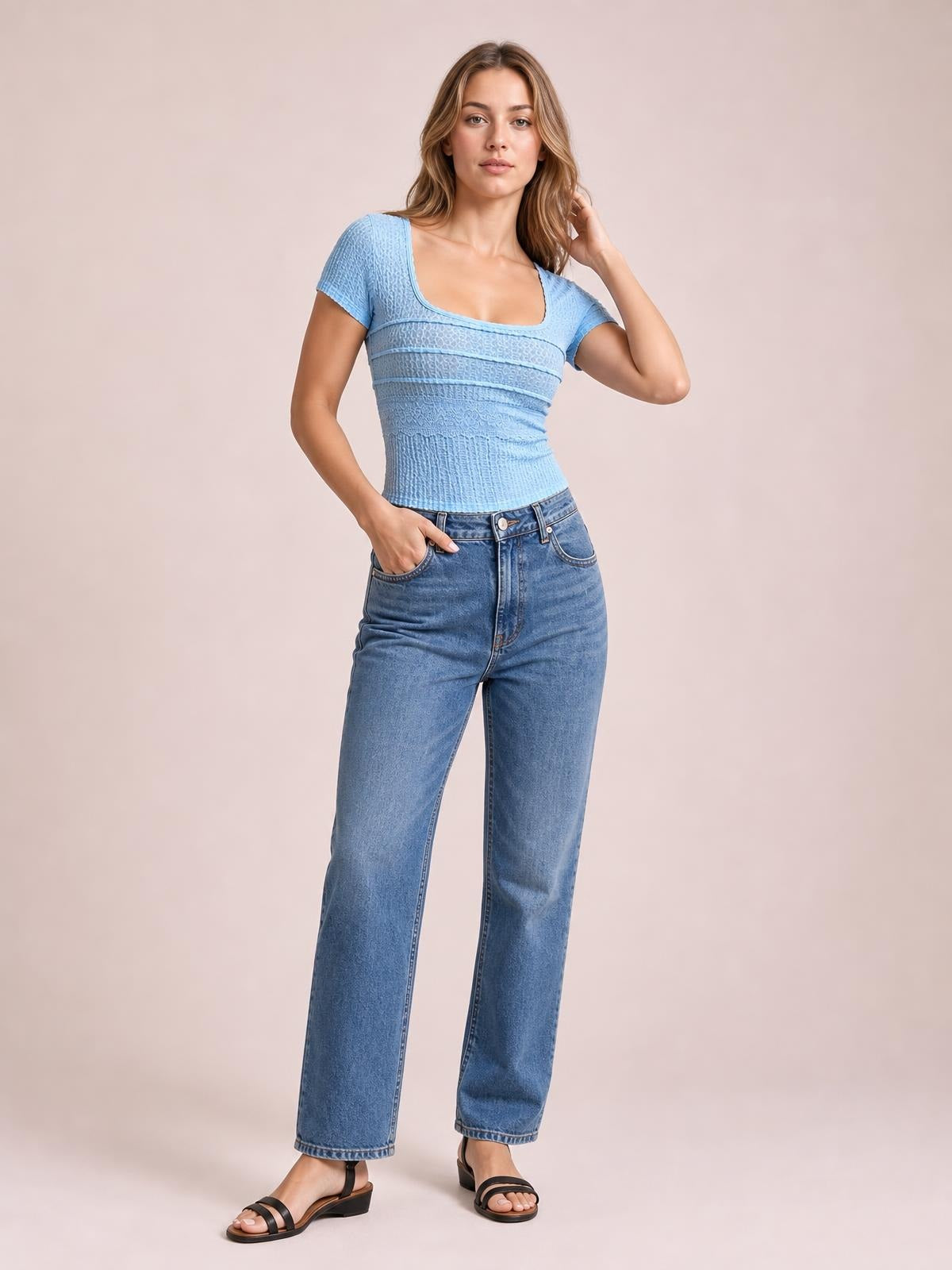 Model wears a light blue lace detail square neck short sleeve T-shirt with a fitted silhouette, textured construction, and one hand resting in her jeans pocket.