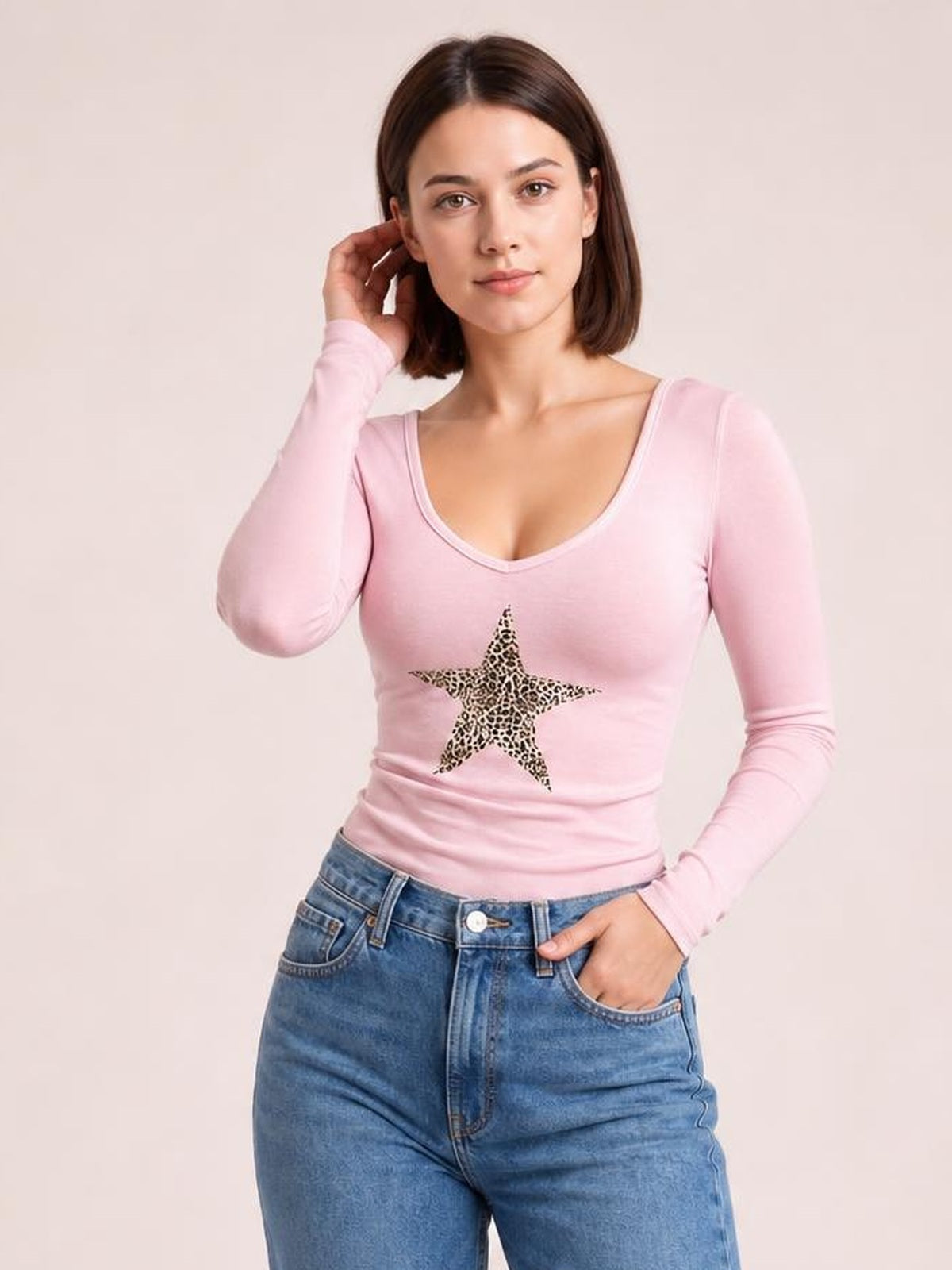 Model poses in a fitted pink leopard star long sleeve T-shirt with a scoop neckline and stretchy silhouette.