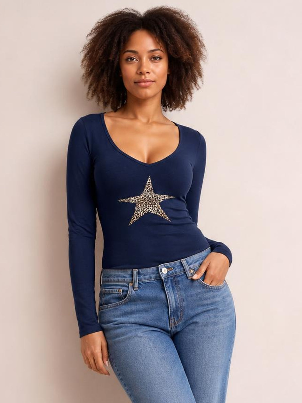 A model poses in a fitted navy Leopard Star long sleeve T-shirt with a deep scoop neckline and bold leopard-print star graphic.