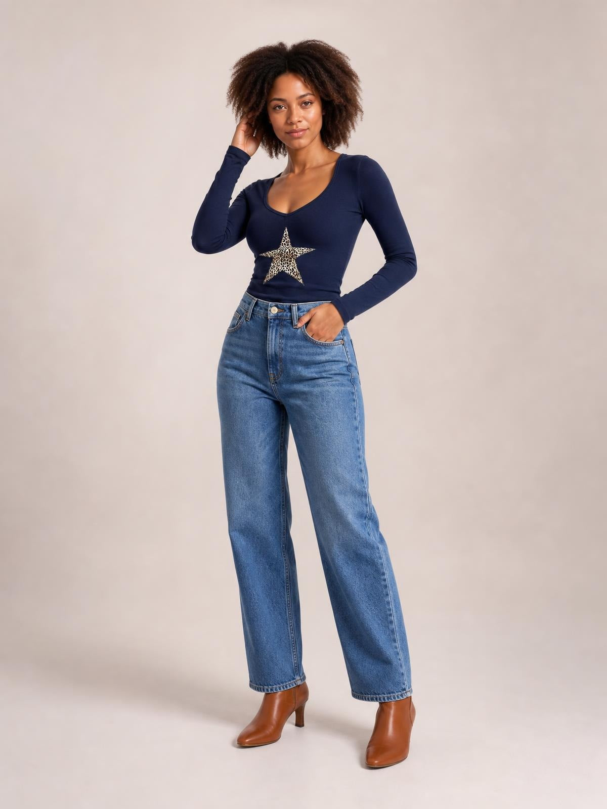 Model wearing a navy long sleeve T-shirt with a V-neck and leopard-print star graphic, fitted silhouette, and stretch construction.