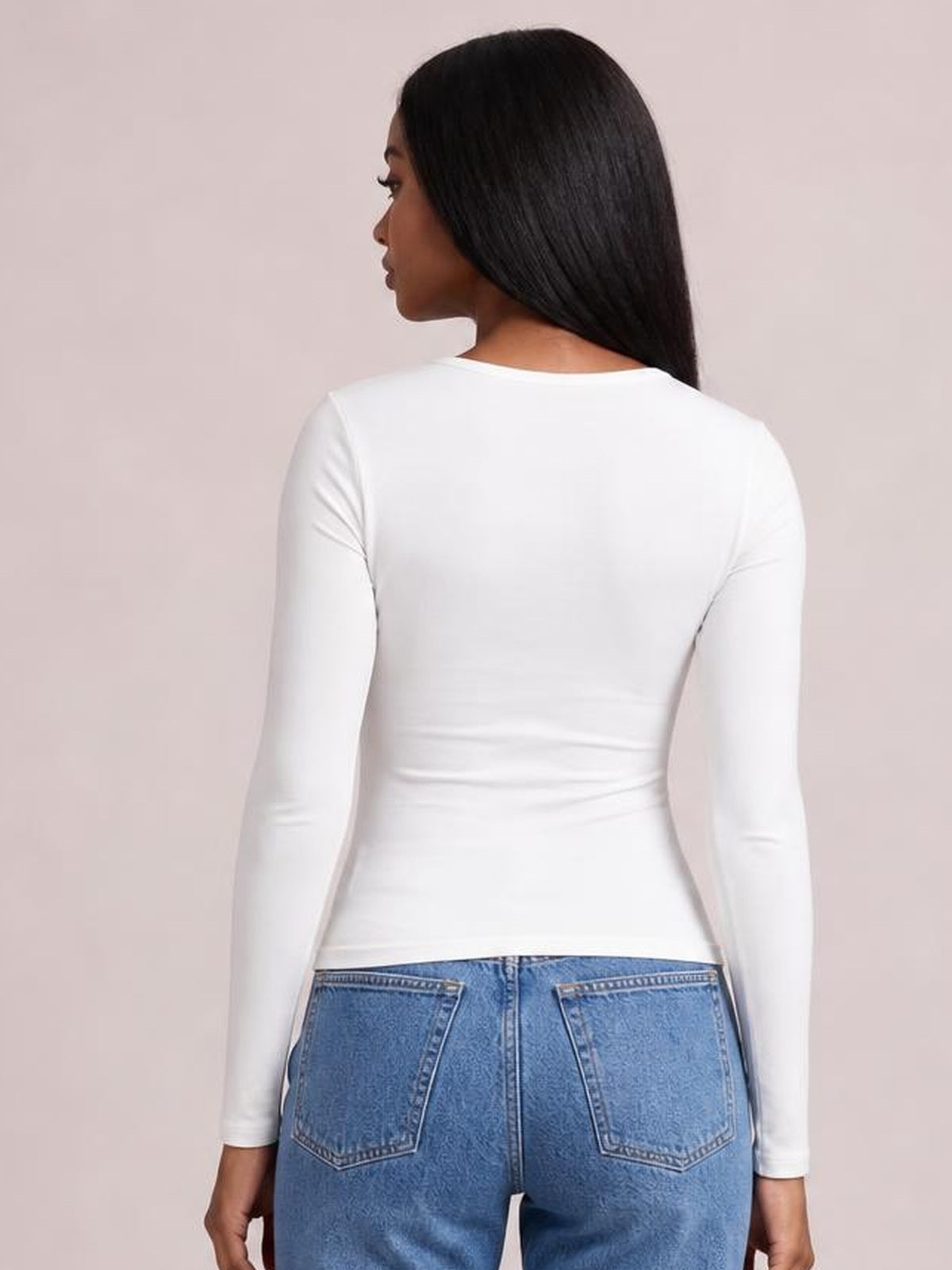 Model shown from behind wearing a white long-sleeve T-shirt with a fitted, stretchy silhouette, crew neckline, smooth opaque fabric, and straight hem.