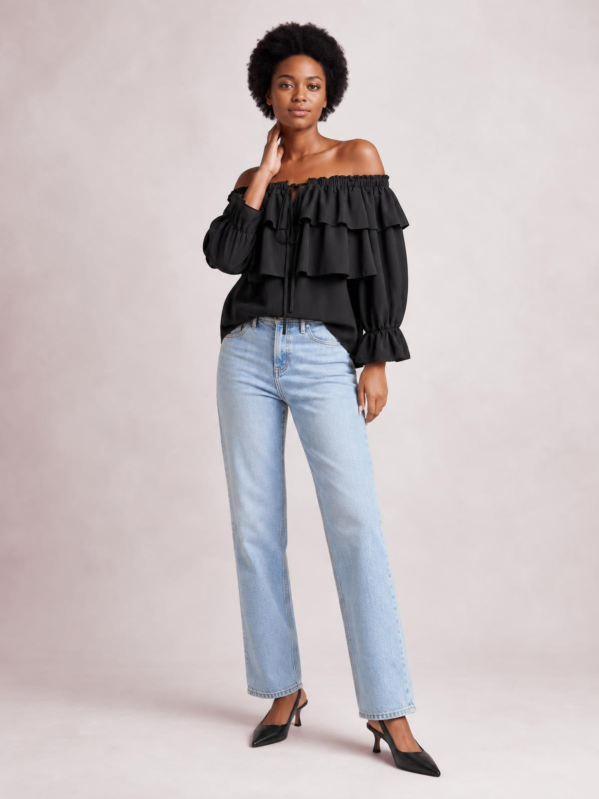 Model poses in a black off-shoulder flounce sleeve blouse with layered ruffles, a drawstring neckline, and gathered cuffs.