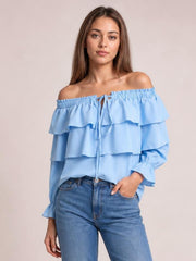Model wearing a light blue off-shoulder blouse with layered ruffled flounce sleeves, a drawstring neckline, and a relaxed silhouette.