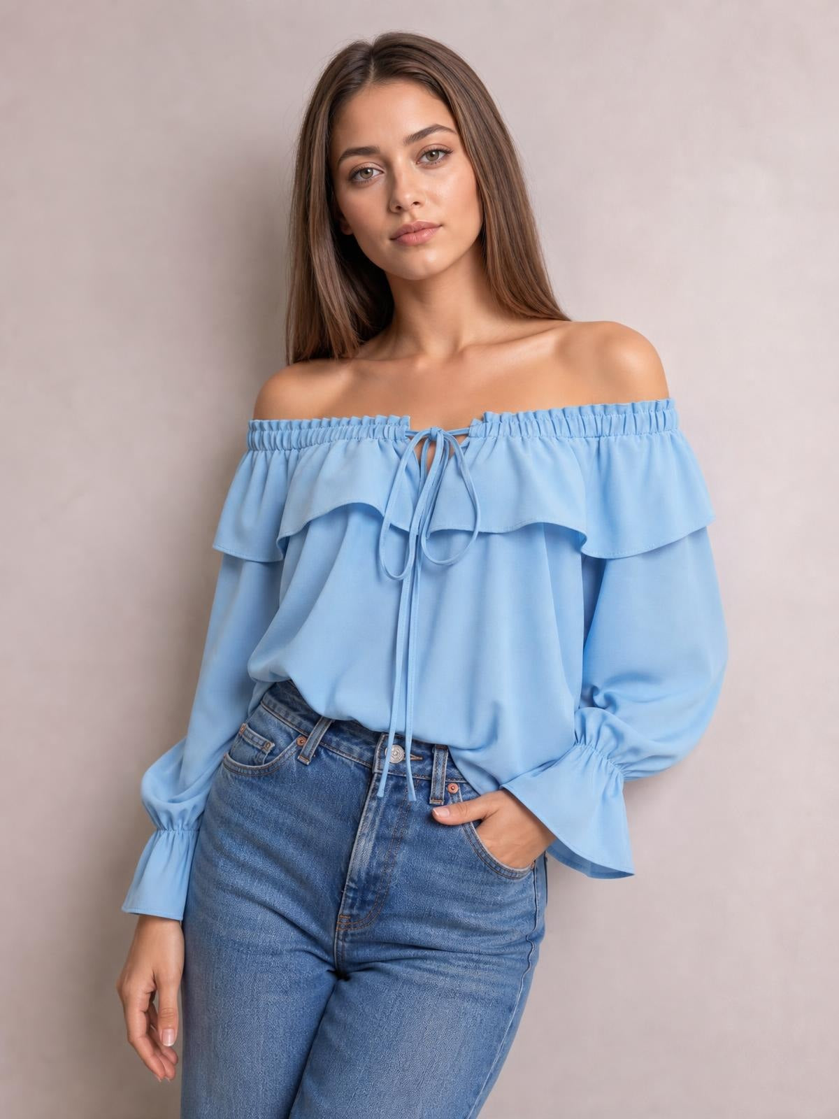 Model poses in a light blue off-shoulder blouse with ruffled flounce sleeves, gathered cuffs, a relaxed silhouette, and a front drawstring tie.