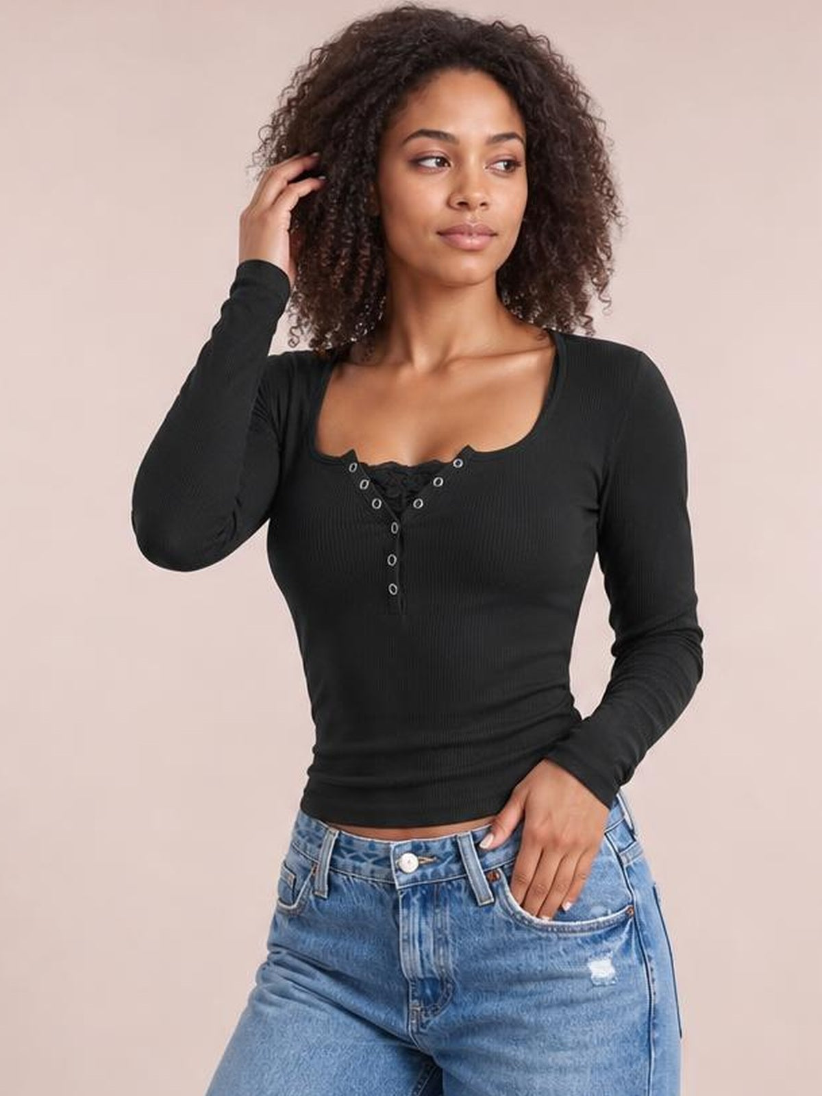 Model wearing a black square-neck half-snap long-sleeve T-shirt with a fitted, stretchy silhouette and buttoned front, posing with one hand in her pocket.