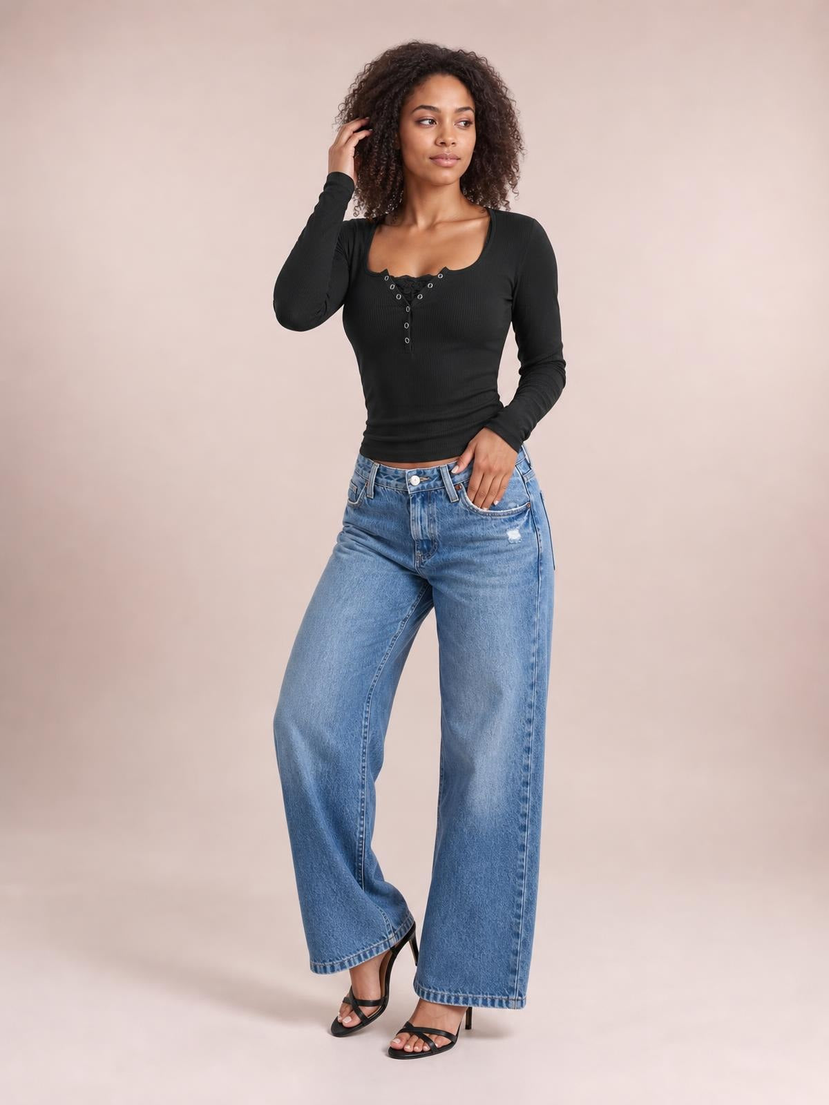 A model poses in a fitted black square-neck half-snap long-sleeve T-shirt with a buttoned front and stretchy ribbed construction.
