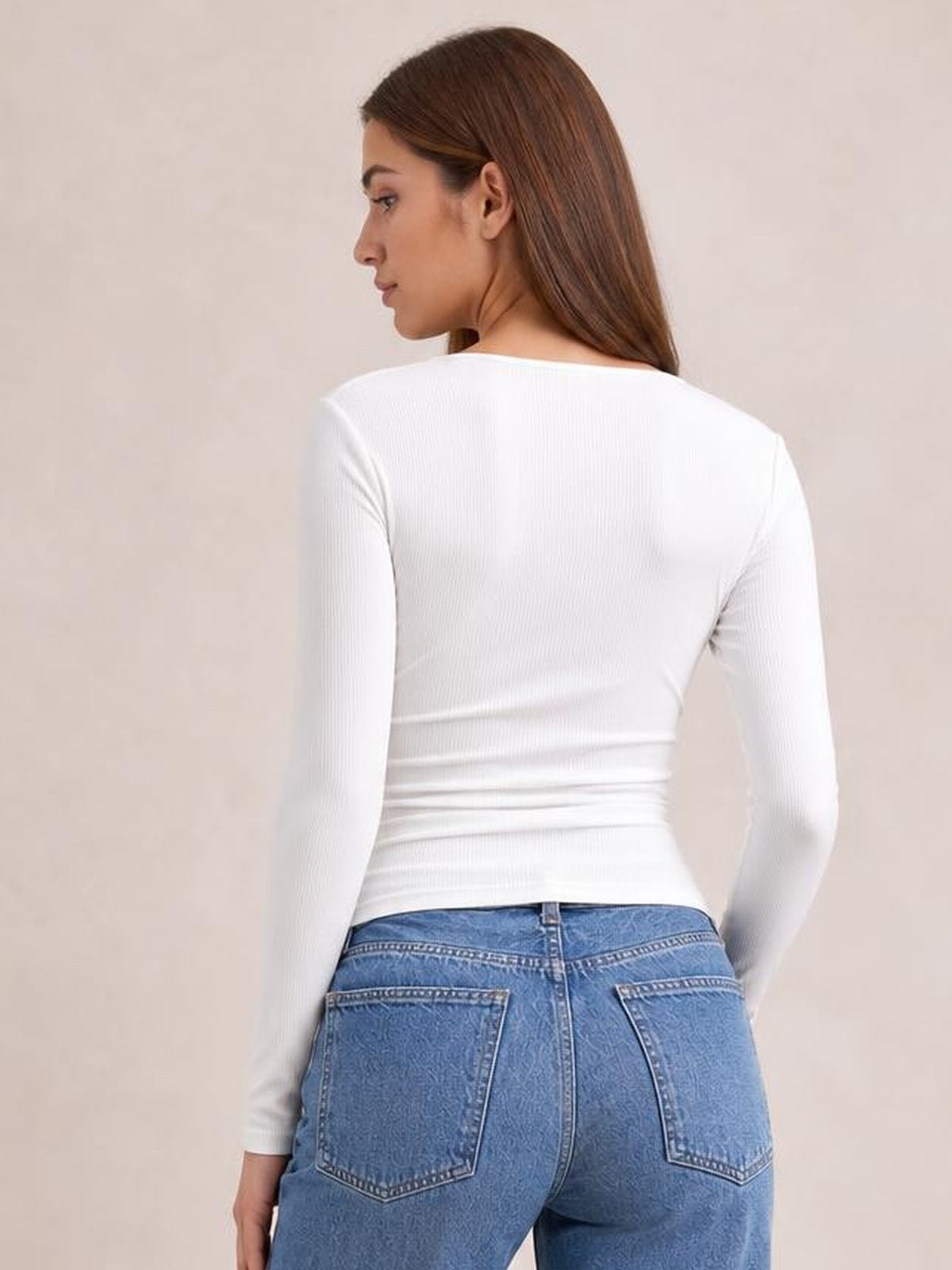 Model in a fitted white square-neck long sleeve T-shirt with a ribbed texture, viewed from behind while looking over her shoulder.