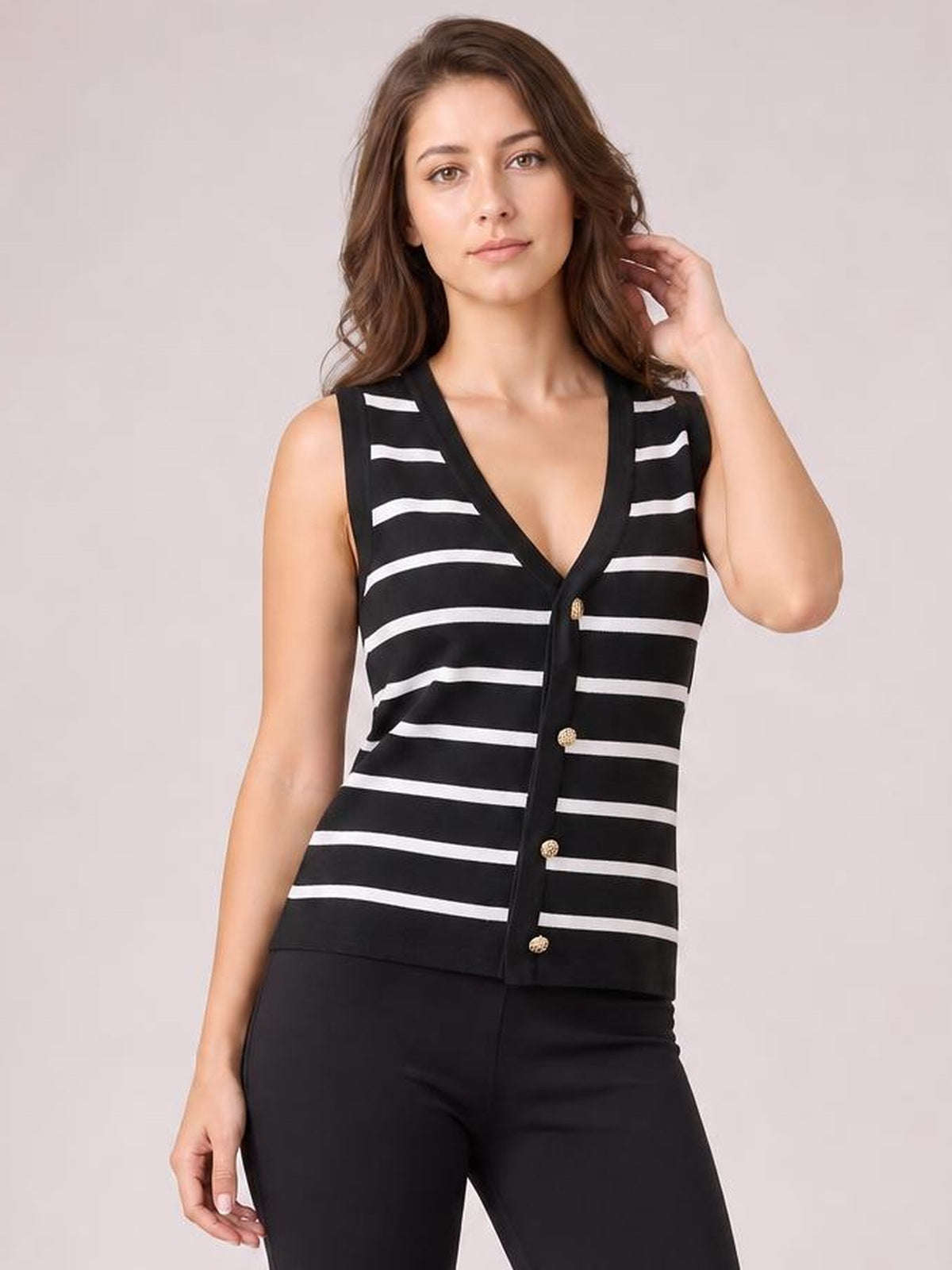 A model poses in a black-and-white striped V-neck knit tank with sleeveless styling, a button-front closure, and a straight silhouette.