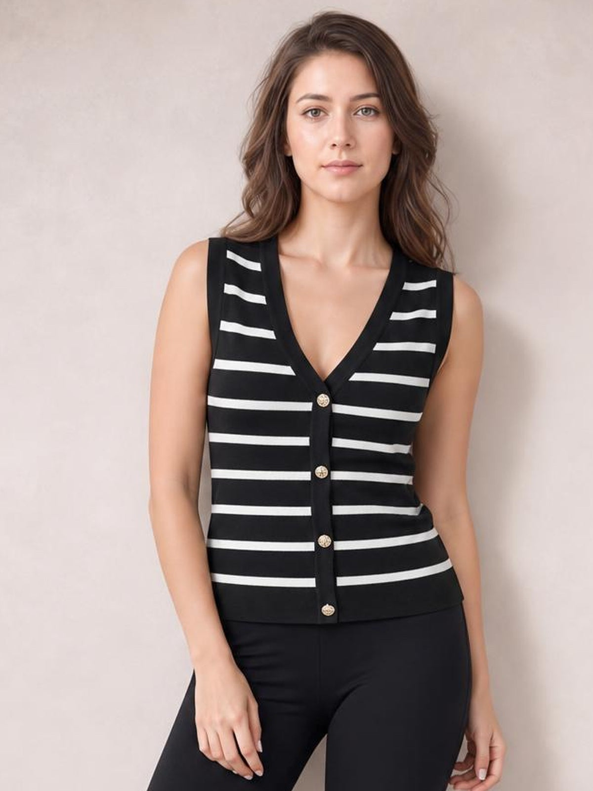 Model wearing a black-and-white striped V-neck knit tank with a fitted silhouette, sleeveless cut, and front button placket, standing with hands relaxed.