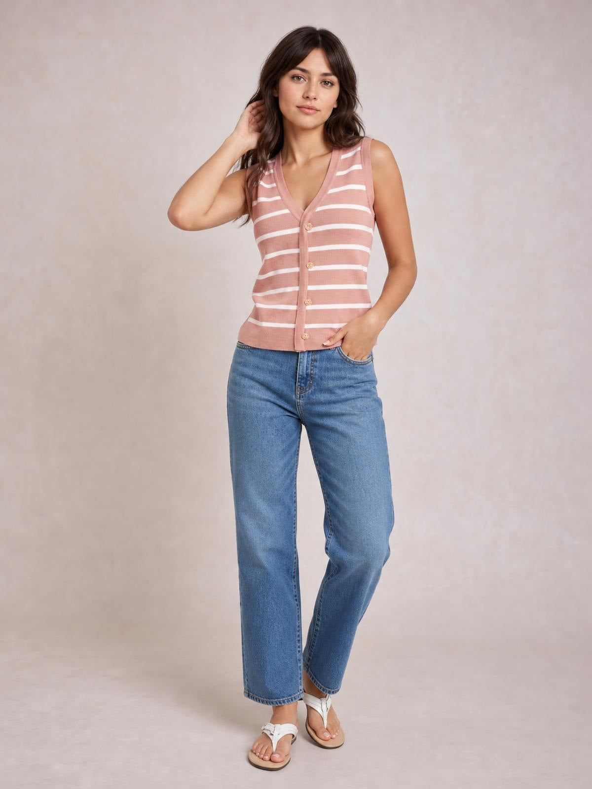 Model poses in a pink and white striped V-neck knit tank with a button front and fitted sleeveless silhouette.