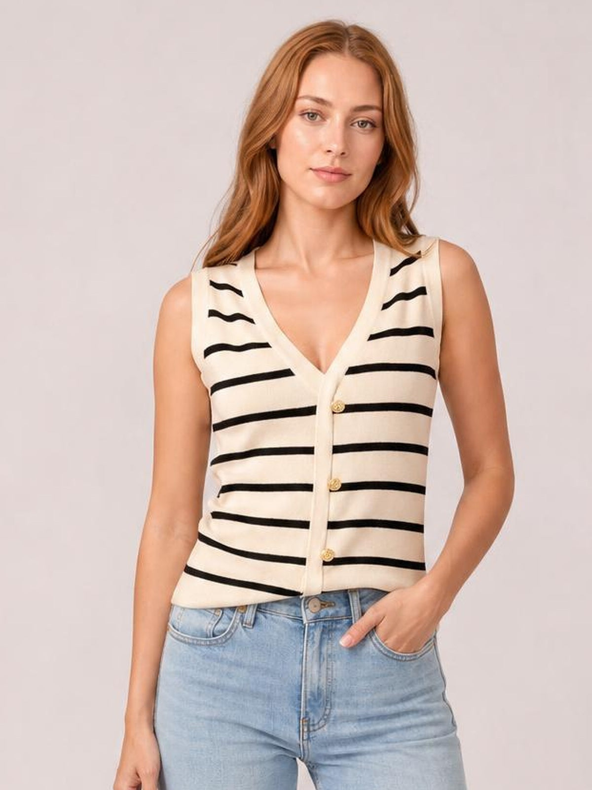 Model poses in a cream striped V-neck knit tank with a fitted sleeveless silhouette, button-front construction, and black horizontal stripes.