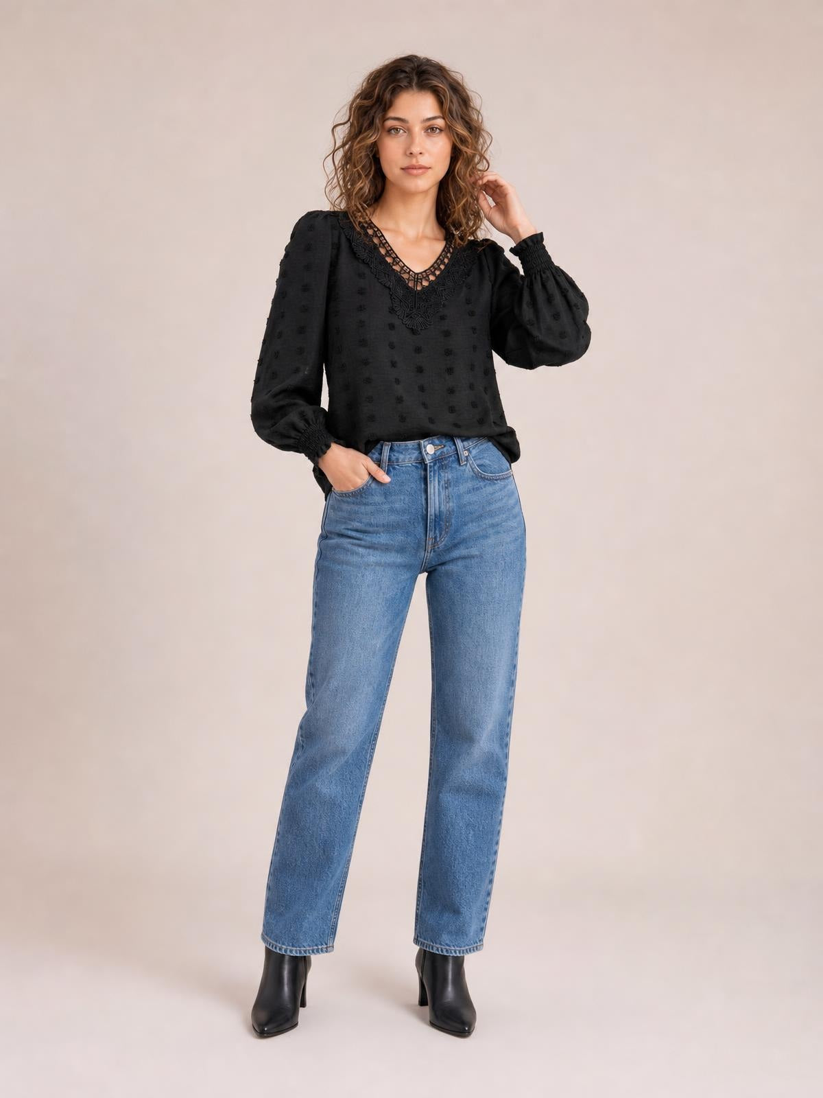Model poses in a black Swiss dot blouse with lace-detail V-neck, long puff sleeves, smocked cuffs, and a relaxed silhouette.