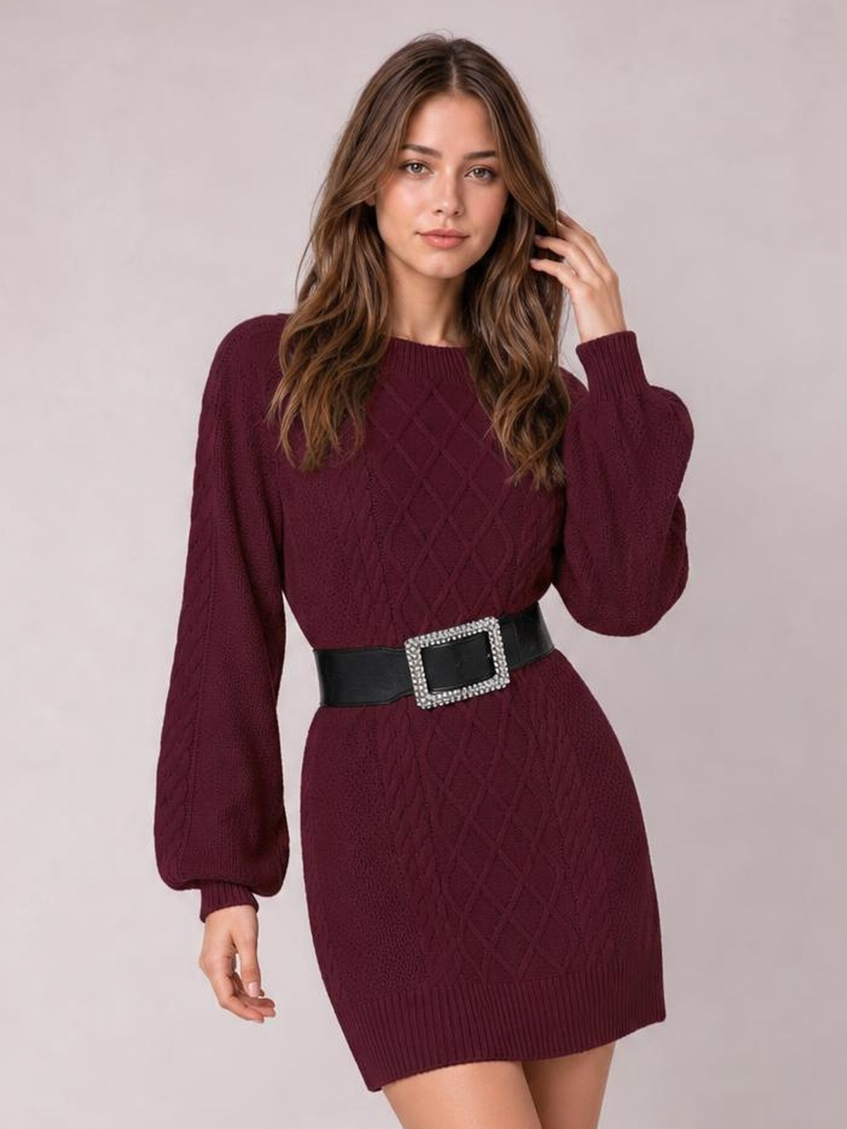 Model wearing a burgundy diamond cable-knit sweater dress with long sleeves, ribbed cuffs and hem, and a fitted above-knee silhouette.