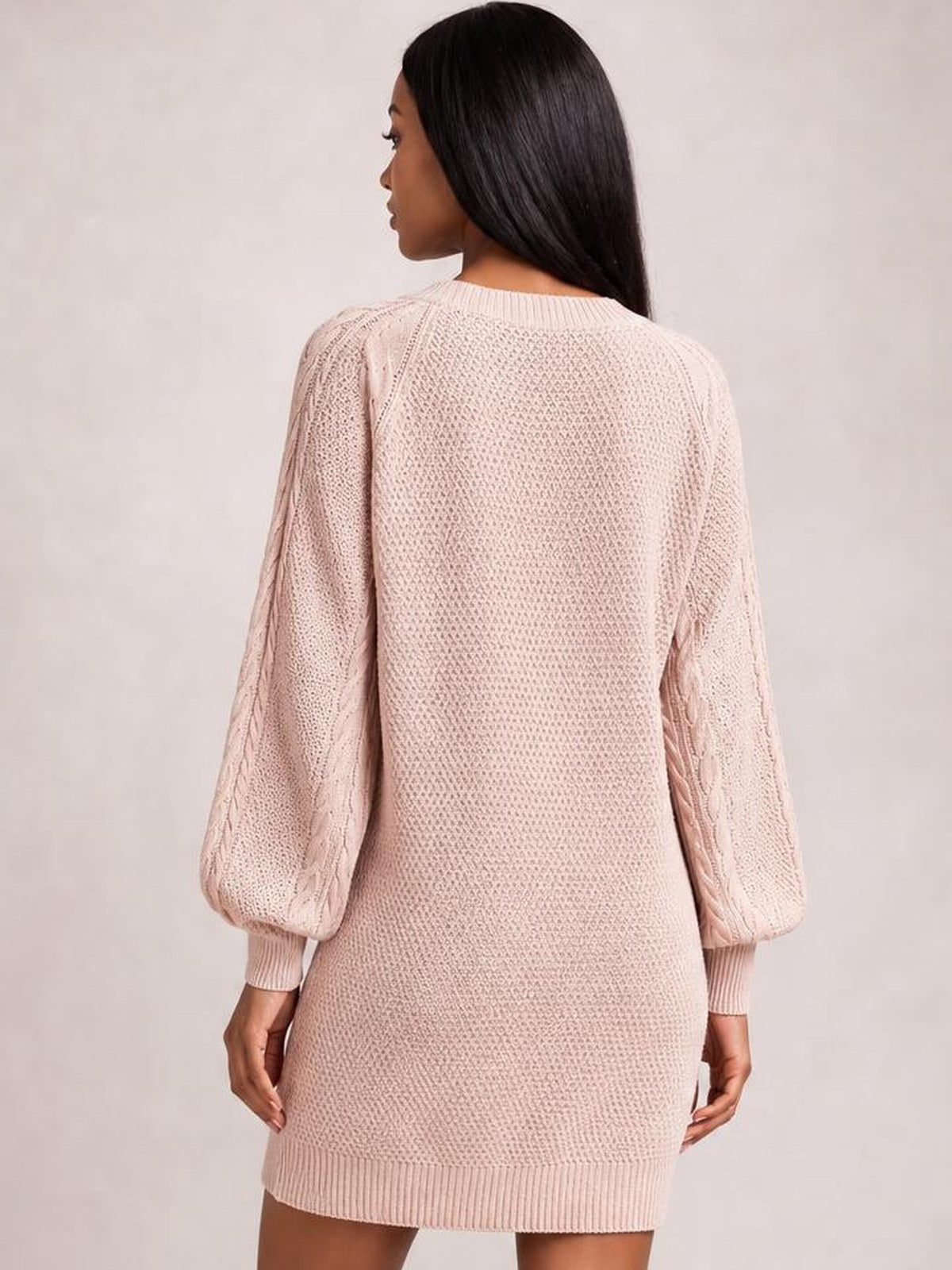 Model shown from behind wearing a light pink diamond cable-knit sweater dress with long sleeves, ribbed crew neck, cuffs, hem, and relaxed silhouette.