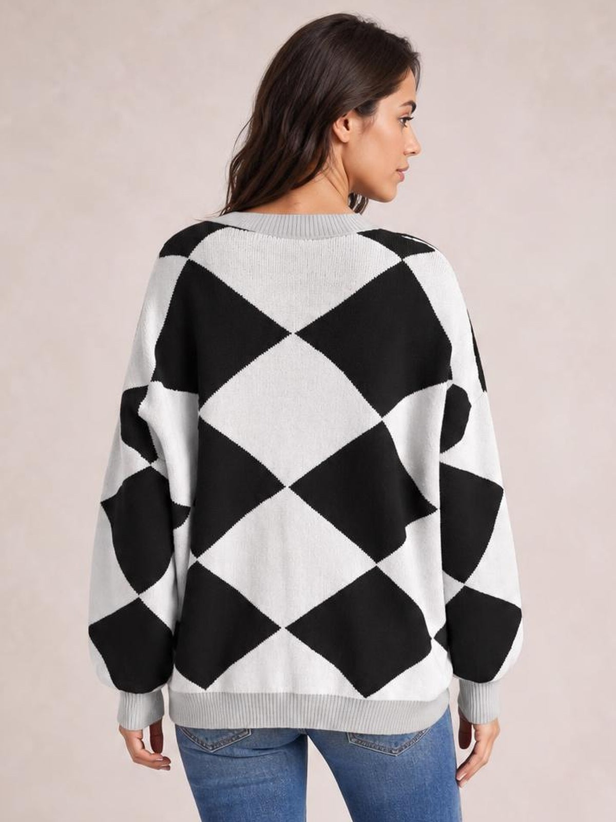 A model shown from the back wears a relaxed black-and-white diamond pattern knit cardigan with a ribbed collar, cuffs, and hem.