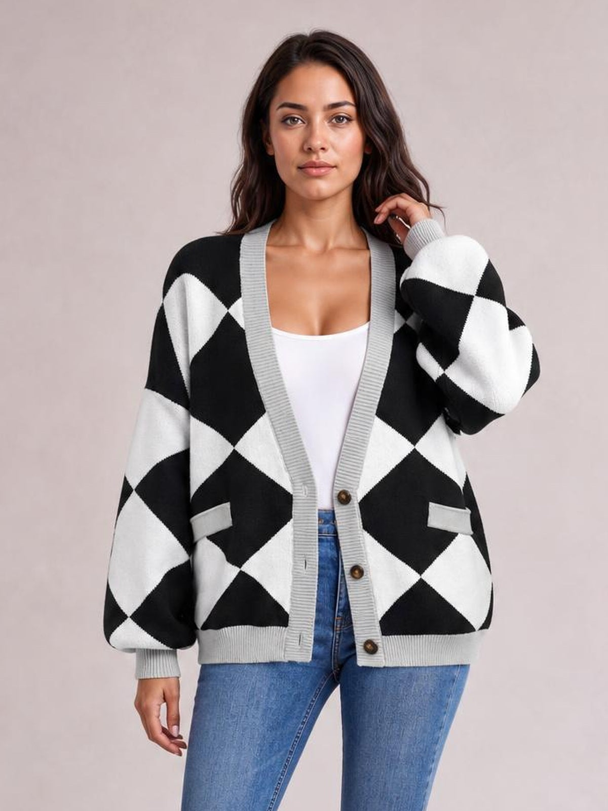 Model wearing a black and white diamond pattern knit cardigan with gray ribbed trim, button front, patch pockets, and a relaxed silhouette over a white top.