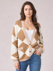 Model poses in a tan and cream diamond pattern button-up knit cardigan with ribbed trim, long sleeves, front pockets, and a relaxed silhouette.