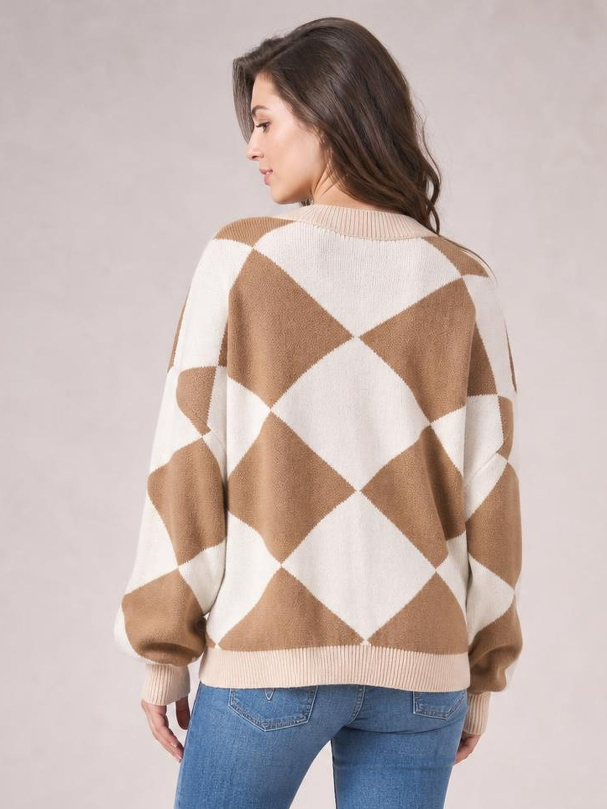 A woman poses in a relaxed-fit knit cardigan with a cream and tan diamond pattern, ribbed collar, cuffs, and hem, viewed from the back.