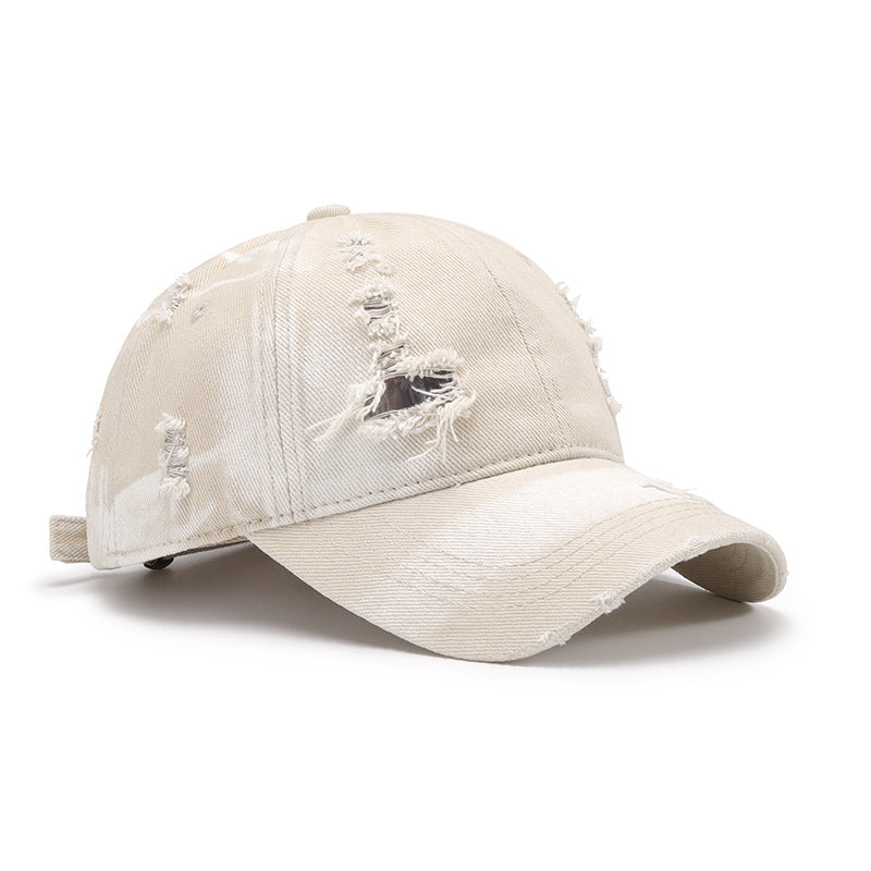Distressed cream cotton baseball cap with a structured six-panel crown, curved brim, frayed accents, and an adjustable back strap.