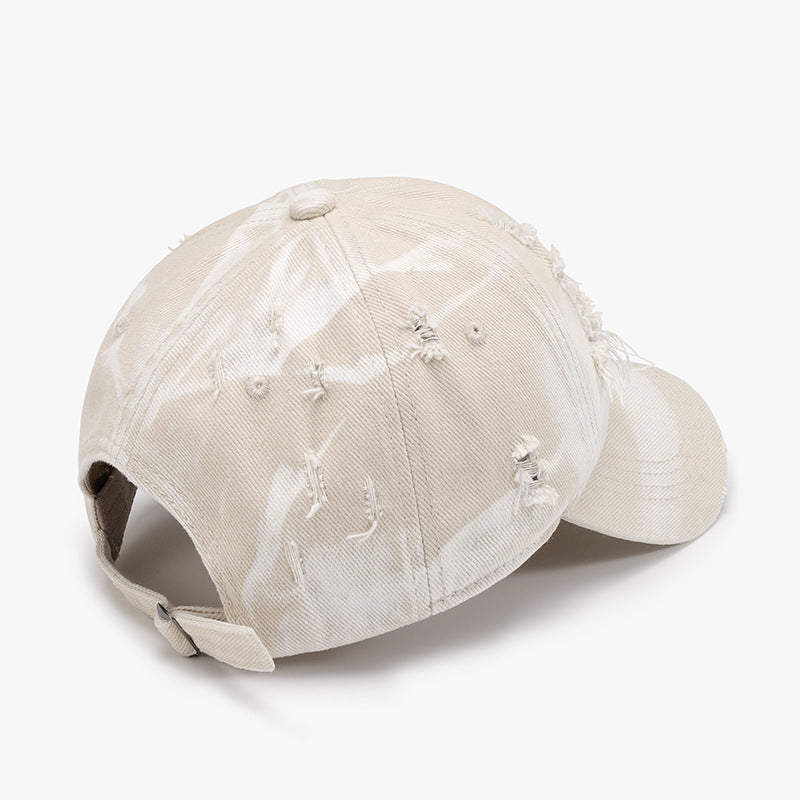 Distressed cream cotton baseball cap with a structured six-panel crown, curved brim, frayed worn details, and an adjustable back strap.