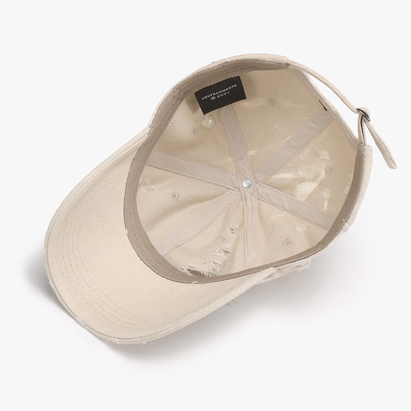 A beige distressed cotton baseball cap shown from below features a six-panel crown, curved brim, frayed accents, and an adjustable back strap.