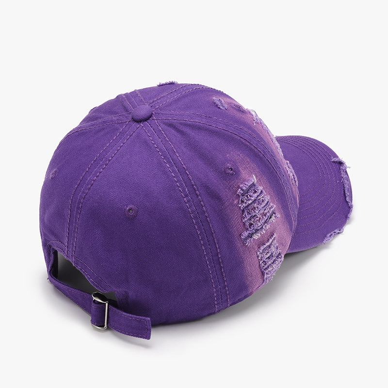 Purple distressed cotton baseball cap with a six-panel crown, curved brim, tonal stitching, frayed details, and an adjustable back strap with metal buckle.