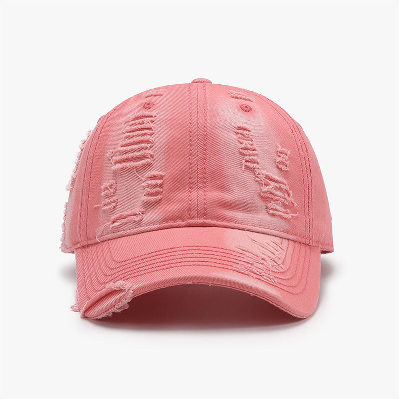 A pink distressed cotton baseball cap with a classic six-panel silhouette, curved brim, tonal stitching, and frayed cutout details across the crown and visor.