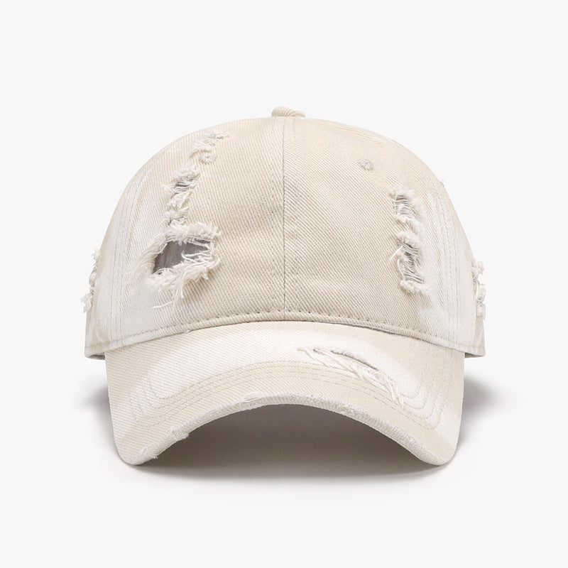 Cream distressed cotton baseball cap with a structured six-panel crown, frayed accents, stitched seams, and a curved brim.