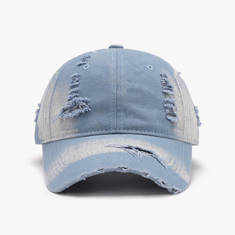 A light blue distressed cotton baseball cap features a structured six-panel crown, curved brim, visible seam lines, and frayed torn accents for a worn-in finish.
