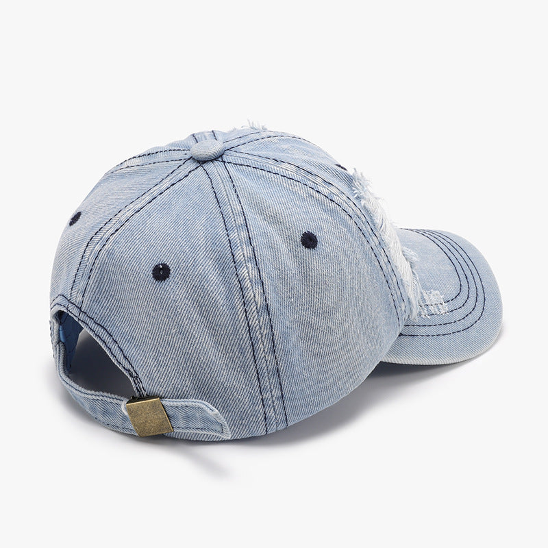 Rear view of a light blue distressed cotton baseball cap showing six-panel seams, ventilation eyelets, a curved brim, and an adjustable back strap with metal slider.