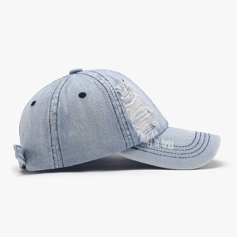 Light blue distressed cotton baseball cap with a structured six-panel crown, visible seam lines, ventilation eyelets, curved brim, and frayed detailing.