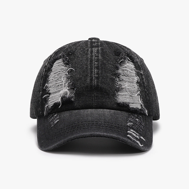 Black distressed cotton baseball cap with a structured six-panel crown, visible seam lines, frayed ripped detailing, ventilation eyelets, and a curved brim.