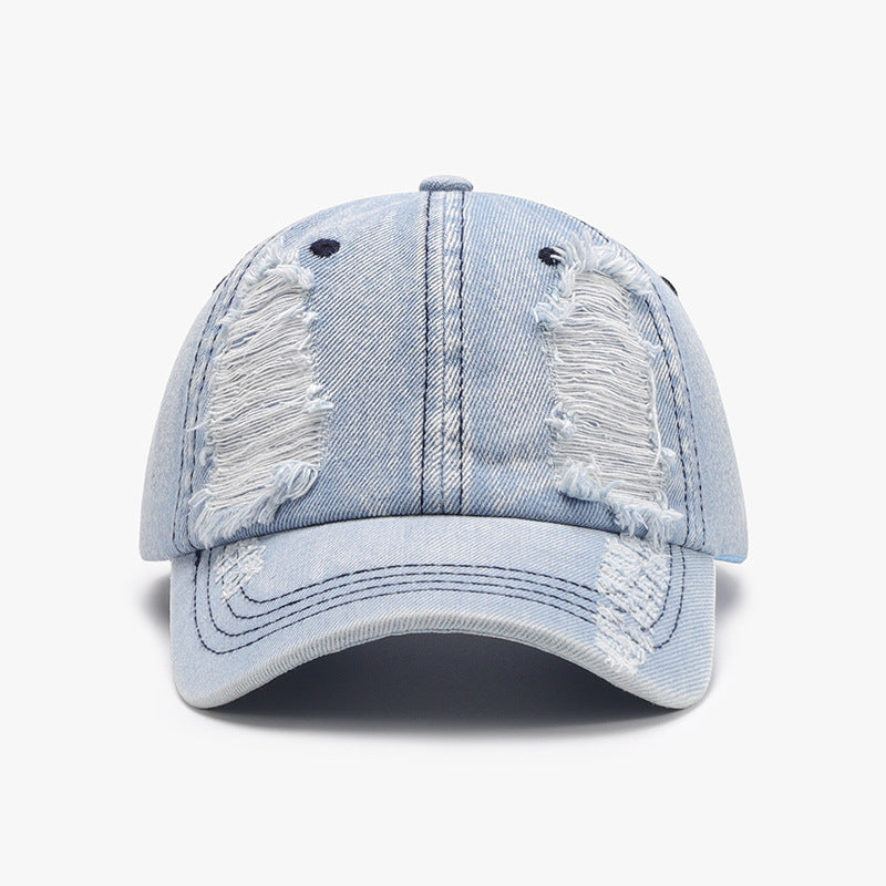 Light-wash distressed cotton baseball cap with a structured six-panel crown, visible seam lines, ventilation eyelets, frayed detailing, and a curved brim.