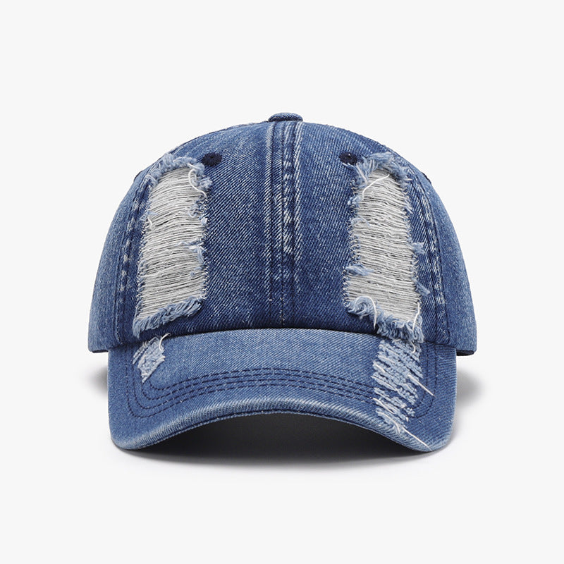 Blue distressed cotton baseball cap with a structured six-panel crown, visible seam lines, ventilation eyelets, and a curved brim.