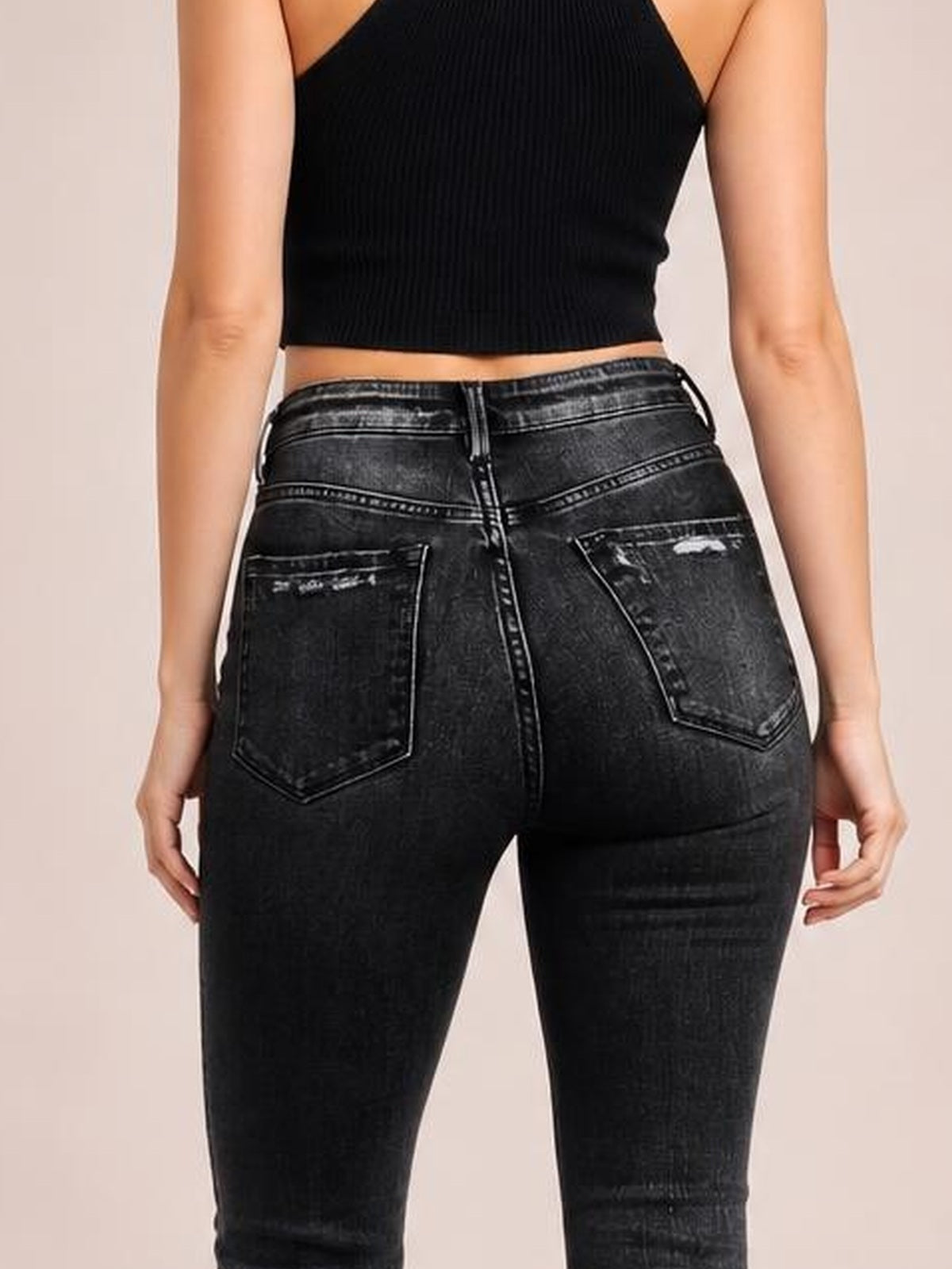 Model shown from behind in black distressed flare jeans with a buttoned waistband, two back pockets, contrast stitching, and a fitted silhouette.