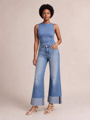 Model wears light-wash distressed high-waisted flare jeans with a fitted hip, wide-leg silhouette, knee tears, five-pocket construction, and raw hems.