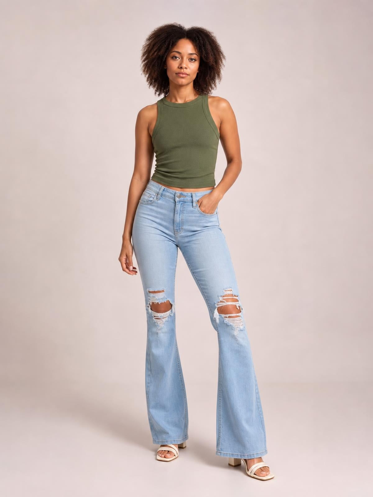 Model poses in light blue distressed jeans with button closure, pockets, ripped knees, and a wide-leg silhouette.